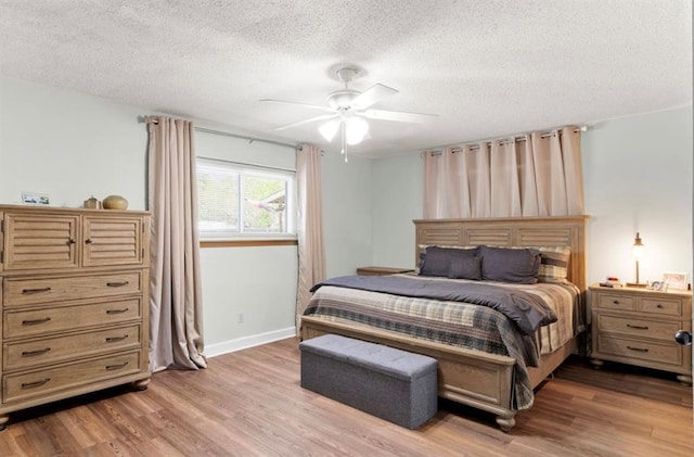 bedroom with a ceiling fan, baseboards, a textured ceiling, and light wood-style floors