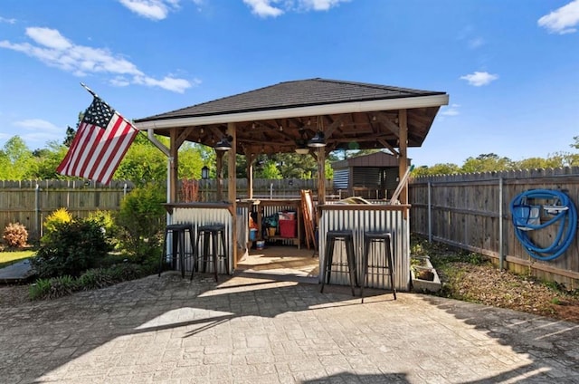 view of patio with a fenced backyard, outdoor dry bar, and a gazebo