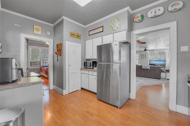 121 S Randlett St, Hobart, OK 73651 - kitchen featuring light wood-type flooring, appliances with stainless steel finishes, white cabinets, and a textured ceiling