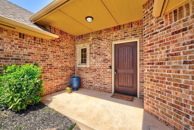 73 Bonaire Dr, Edmond, OK 73013 - entrance to property featuring brick siding, a shingled roof, and a patio