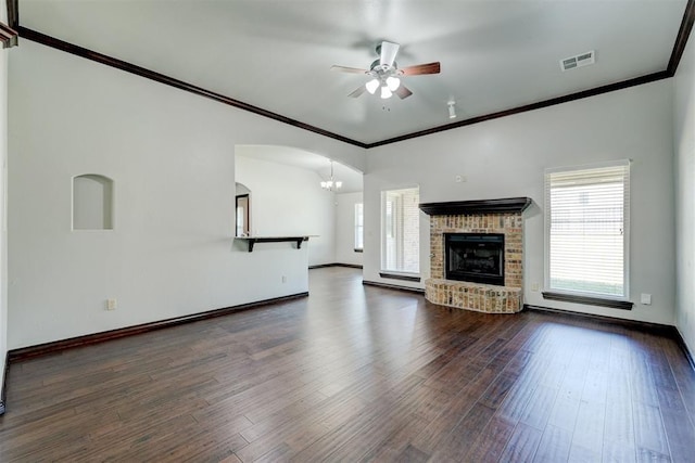 73 Bonaire Dr, Edmond, OK 73013 - unfurnished living room with a ceiling fan, dark wood-style floors, a chandelier, a brick fireplace, and crown molding