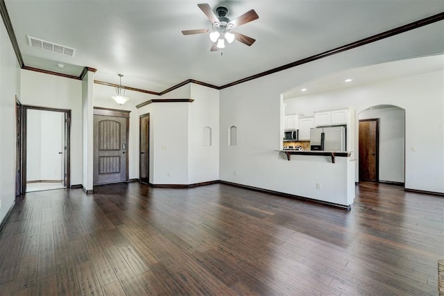 73 Bonaire Dr, Edmond, OK 73013 - unfurnished living room featuring ceiling fan, arched walkways, dark wood finished floors, crown molding, and baseboards