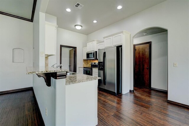 73 Bonaire Dr, Edmond, OK 73013 - kitchen featuring appliances with stainless steel finishes, a sink, a peninsula, dark wood finished floors, and white cabinets