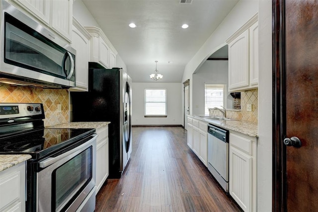 73 Bonaire Dr, Edmond, OK 73013 - kitchen featuring appliances with stainless steel finishes, a chandelier, white cabinets, dark wood-style flooring, and a sink