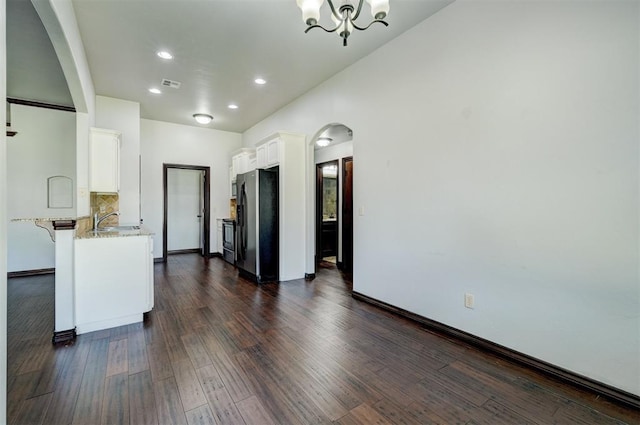 73 Bonaire Dr, Edmond, OK 73013 - unfurnished living room with a chandelier, dark wood-style floors, recessed lighting, a sink, and arched walkways