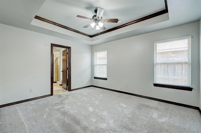 73 Bonaire Dr, Edmond, OK 73013 - spare room featuring a raised ceiling, ceiling fan, ornamental molding, light carpet, and baseboards