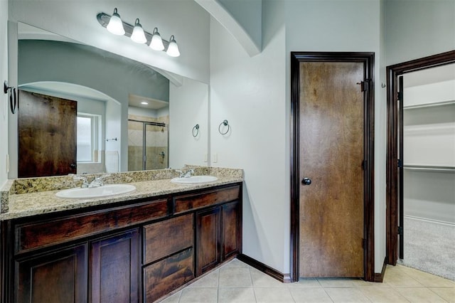 73 Bonaire Dr, Edmond, OK 73013 - full bathroom with a stall shower, a walk in closet, tile patterned flooring, double vanity, and baseboards