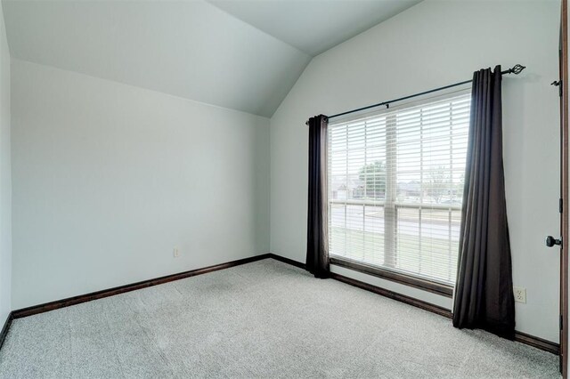 73 Bonaire Dr, Edmond, OK 73013 - spare room with light colored carpet, vaulted ceiling, and baseboards
