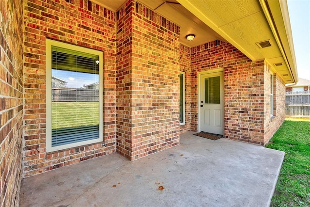 73 Bonaire Dr, Edmond, OK 73013 - view of exterior entry with brick siding, a patio, and fence