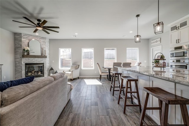 living room with dark wood-type flooring, ceiling fan, recessed lighting, and a healthy amount of sunlight