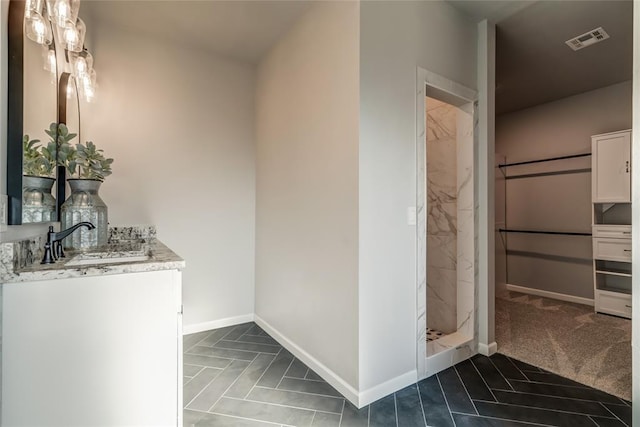 bathroom featuring visible vents, baseboards, a shower stall, and vanity