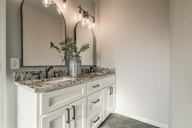 full bathroom with double vanity, baseboards, and a sink