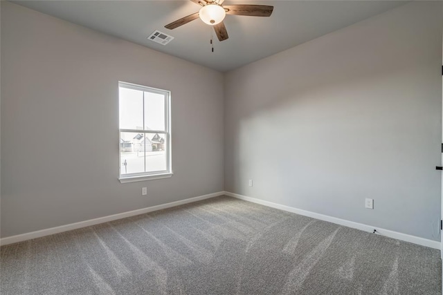 carpeted spare room with baseboards, a ceiling fan, and visible vents
