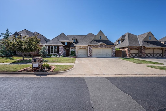 french provincial home featuring a front yard, an attached garage, stone siding, fence, and driveway