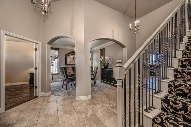 foyer entrance with arched walkways, a high ceiling, baseboards, and a notable chandelier