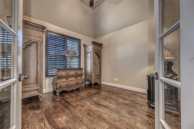 interior space featuring dark wood-style flooring, baseboards, and a high ceiling