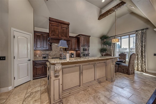 kitchen with baseboards, dark brown cabinetry, a center island with sink, decorative backsplash, and light stone counters