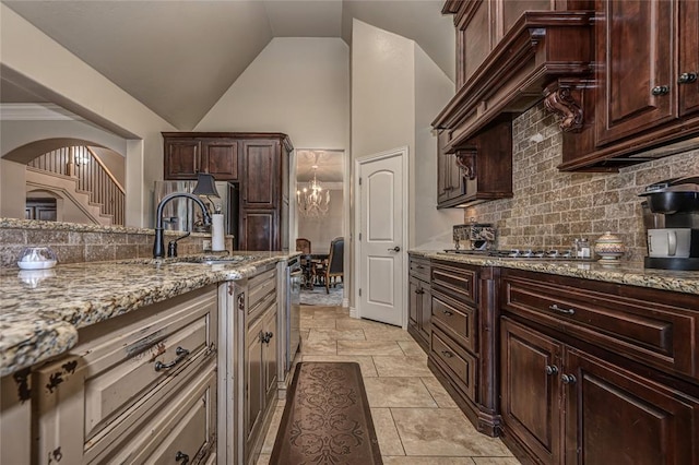 kitchen with tasteful backsplash, light stone countertops, lofted ceiling, arched walkways, and a sink