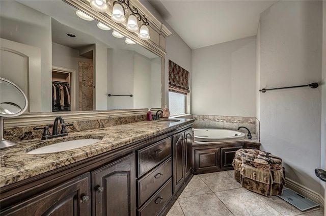 full bath with a sink, tile patterned floors, double vanity, and a bath