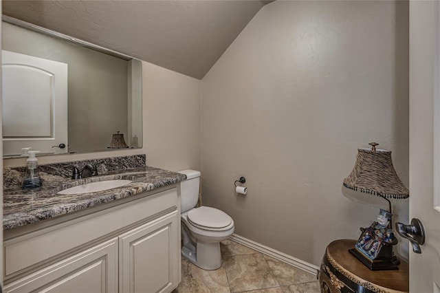 bathroom with toilet, vanity, baseboards, and lofted ceiling