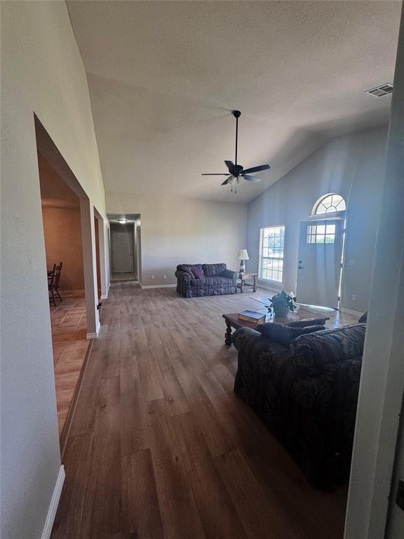 705 Cambridge Dr, Sulphur, OK 73086 - living room featuring visible vents, wood finished floors, baseboards, a ceiling fan, and vaulted ceiling