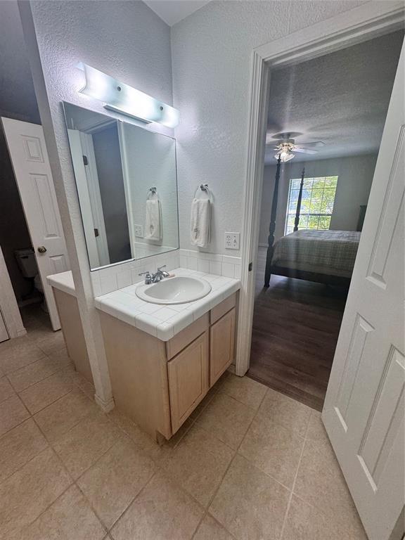 705 Cambridge Dr, Sulphur, OK 73086 - ensuite bathroom with ensuite bathroom, a ceiling fan, tile patterned floors, vanity, and a textured wall