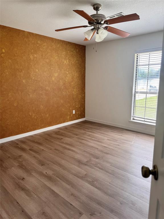 705 Cambridge Dr, Sulphur, OK 73086 - empty room with baseboards, an accent wall, a ceiling fan, and wood finished floors
