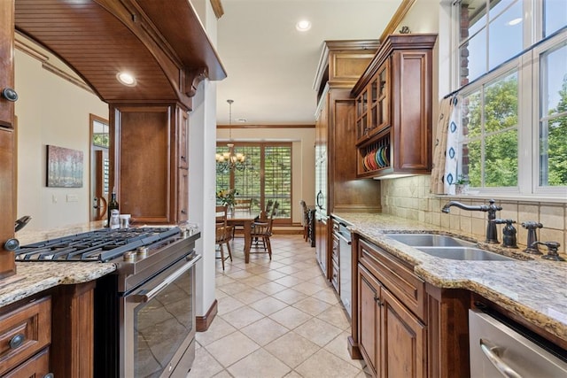 3920 Creek Bank Dr, Edmond, OK 73003 - kitchen with stainless steel appliances, a chandelier, healthy amount of natural light, brown cabinetry, and ornamental molding