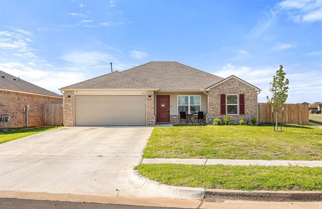 ranch-style house with fence, a front lawn, brick siding, a garage, and driveway