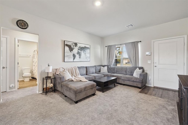 carpeted living area featuring visible vents and baseboards