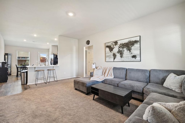 living room with recessed lighting, light colored carpet, and baseboards