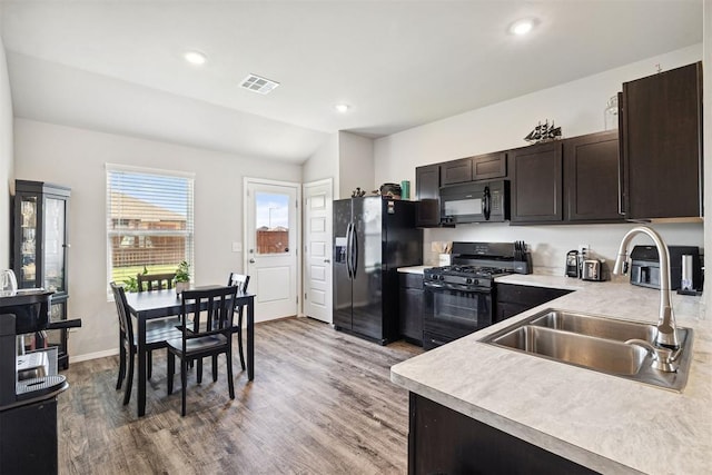 kitchen featuring light countertops, visible vents, a sink, and black appliances