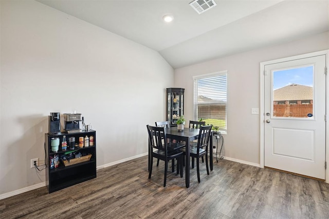 dining space featuring visible vents, baseboards, vaulted ceiling, and wood finished floors