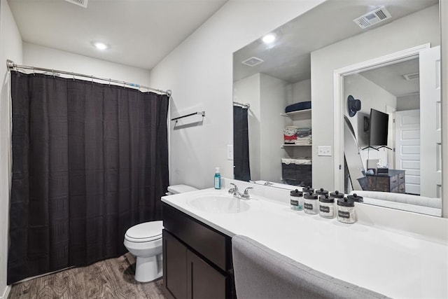 bathroom featuring toilet, wood finished floors, vanity, and visible vents