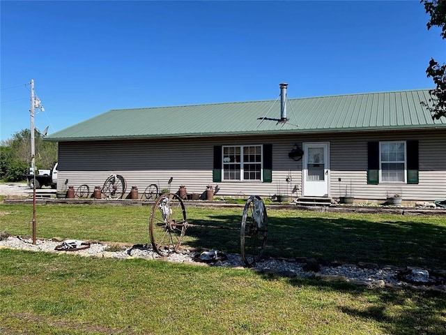 view of front facade featuring entry steps, metal roof, and a front yard