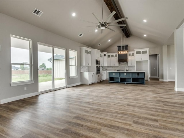 unfurnished living room featuring ceiling fan, baseboards, visible vents, and vaulted ceiling with beams