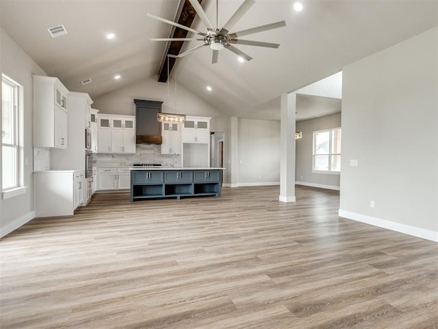 unfurnished living room featuring baseboards, ceiling fan, lofted ceiling with beams, and light wood-style flooring
