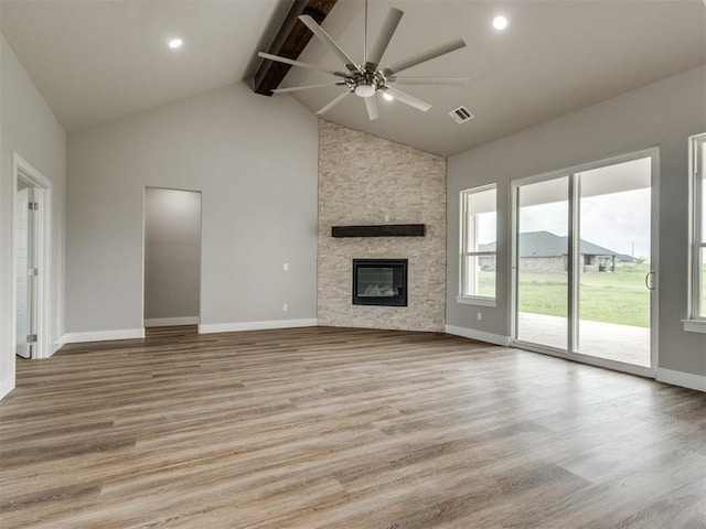 unfurnished living room with a ceiling fan, visible vents, light wood-type flooring, high vaulted ceiling, and beamed ceiling