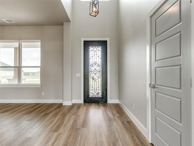 foyer featuring baseboards, visible vents, and wood finished floors