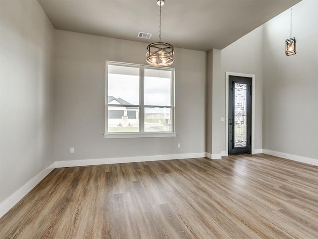 interior space with visible vents, baseboards, wood finished floors, and a notable chandelier
