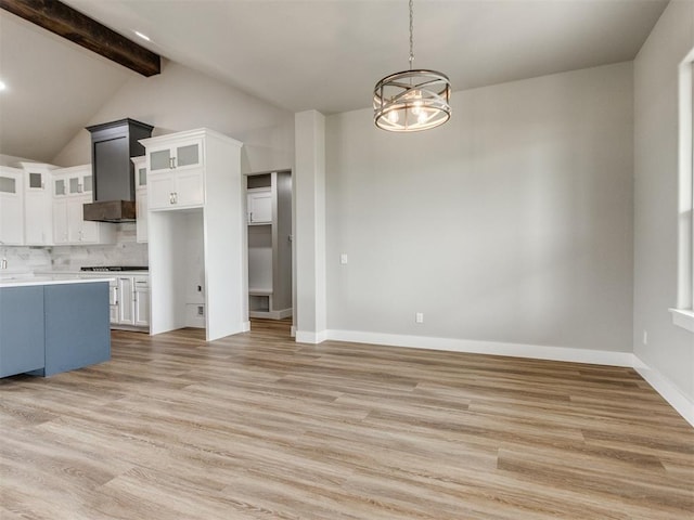 kitchen featuring tasteful backsplash, a chandelier, light wood-style flooring, white cabinetry, and cooktop