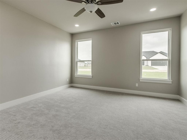 spare room featuring visible vents, light carpet, baseboards, recessed lighting, and a ceiling fan