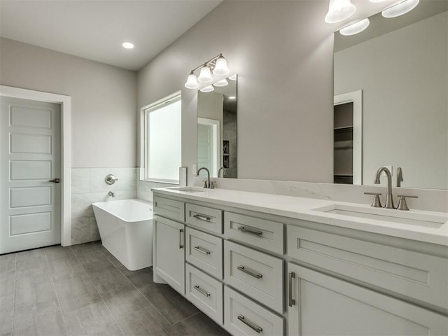 full bathroom with double vanity, a sink, recessed lighting, and a soaking tub