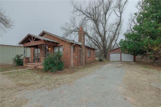 1319 S Division St, Guthrie, OK 73044 - view of front facade with an outdoor structure, a detached garage, a chimney, and a porch