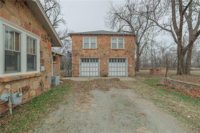 1319 S Division St, Guthrie, OK 73044 - view of side of home featuring stone siding, dirt driveway, and central air condition unit