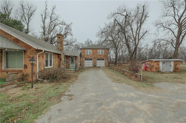 1319 S Division St, Guthrie, OK 73044 - view of property exterior featuring driveway, a chimney, stone siding, and a shingled roof