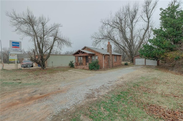 1319 S Division St, Guthrie, OK 73044 - view of front of property featuring an outdoor structure, a garage, driveway, and a chimney