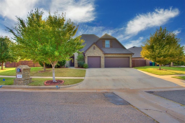 traditional-style house with a garage, fence, a front lawn, brick siding, and driveway
