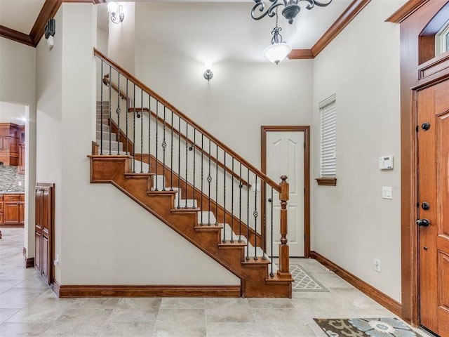foyer with crown molding, a towering ceiling, baseboards, and stairs