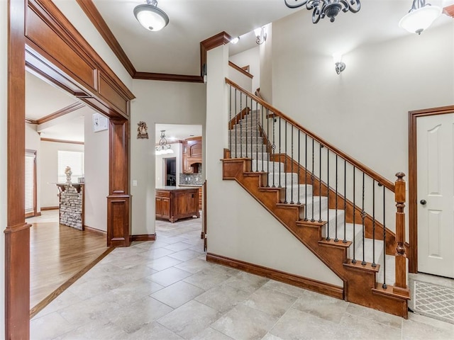 stairway featuring a towering ceiling, baseboards, and ornamental molding
